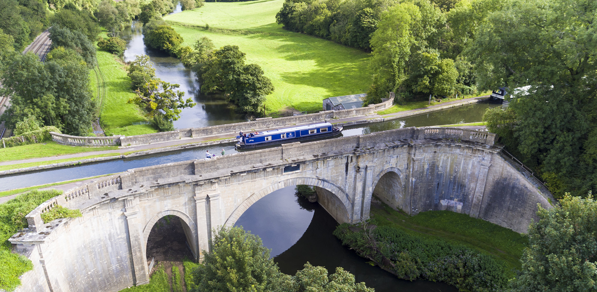 Blue canal boat passing over an aqueduc