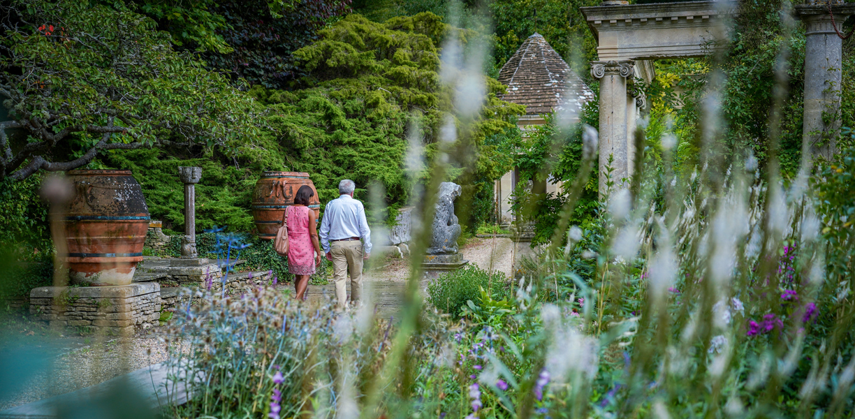 A couple walk through the artistic gardens at Iford Manor