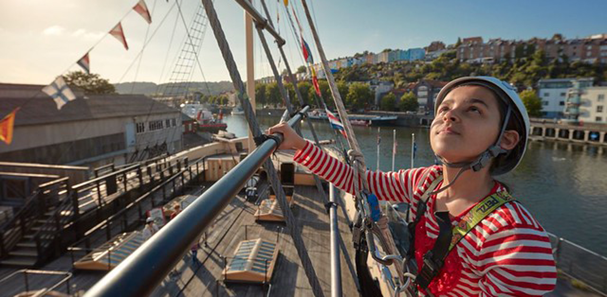 person climbing the rigging with Bristol in the background