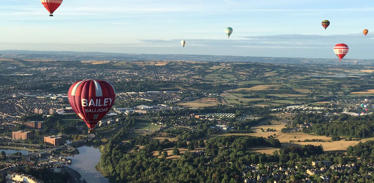 Hot air balloons flying over houses and fields