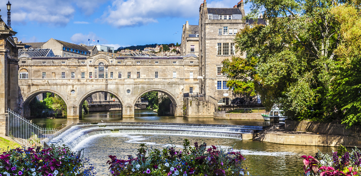Pulteney Bridge in Bath with blue skies above and flowers