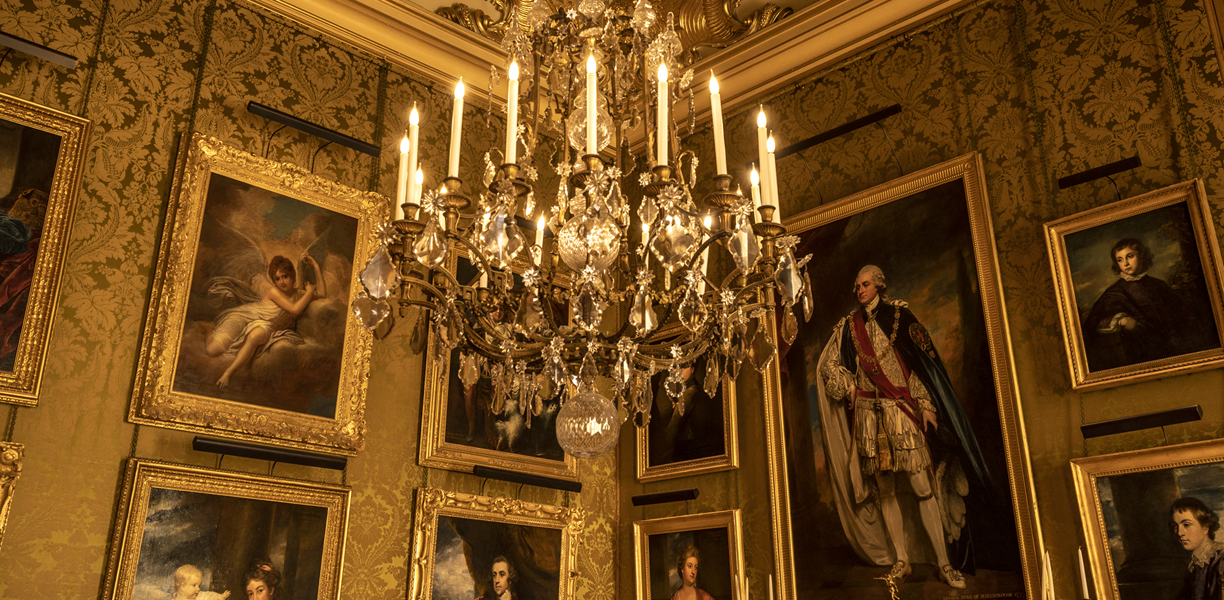 Room with gold-framed portraits and chandelier