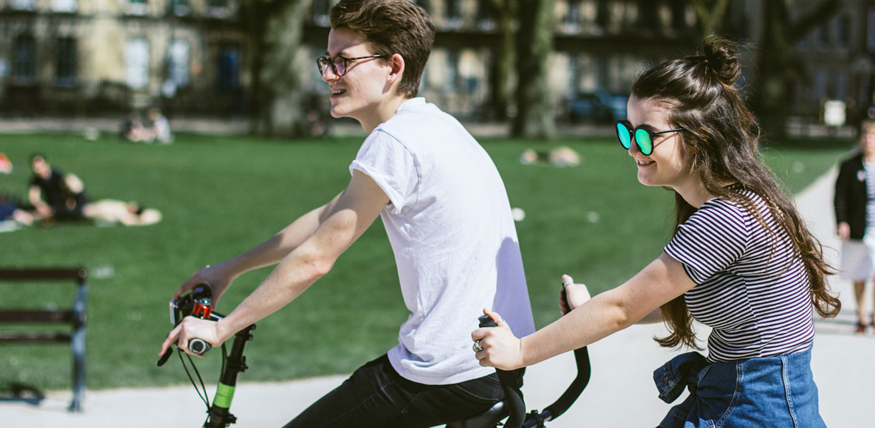 A young man and young woman riding a tandem bicycle 