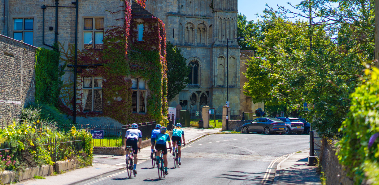 A group of cyclists passing historic buildings