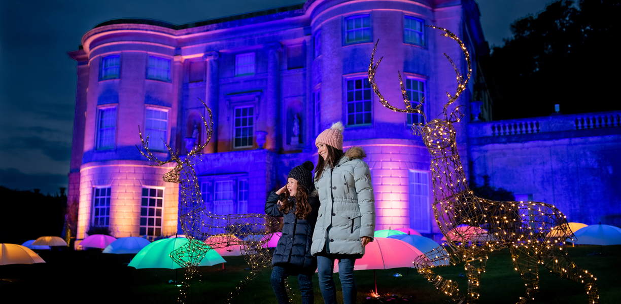Family look at illuminated stone front of museum