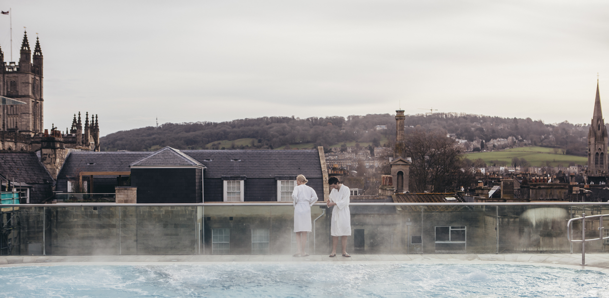 A couple admire the view over Bath from the rooftop swimming pool