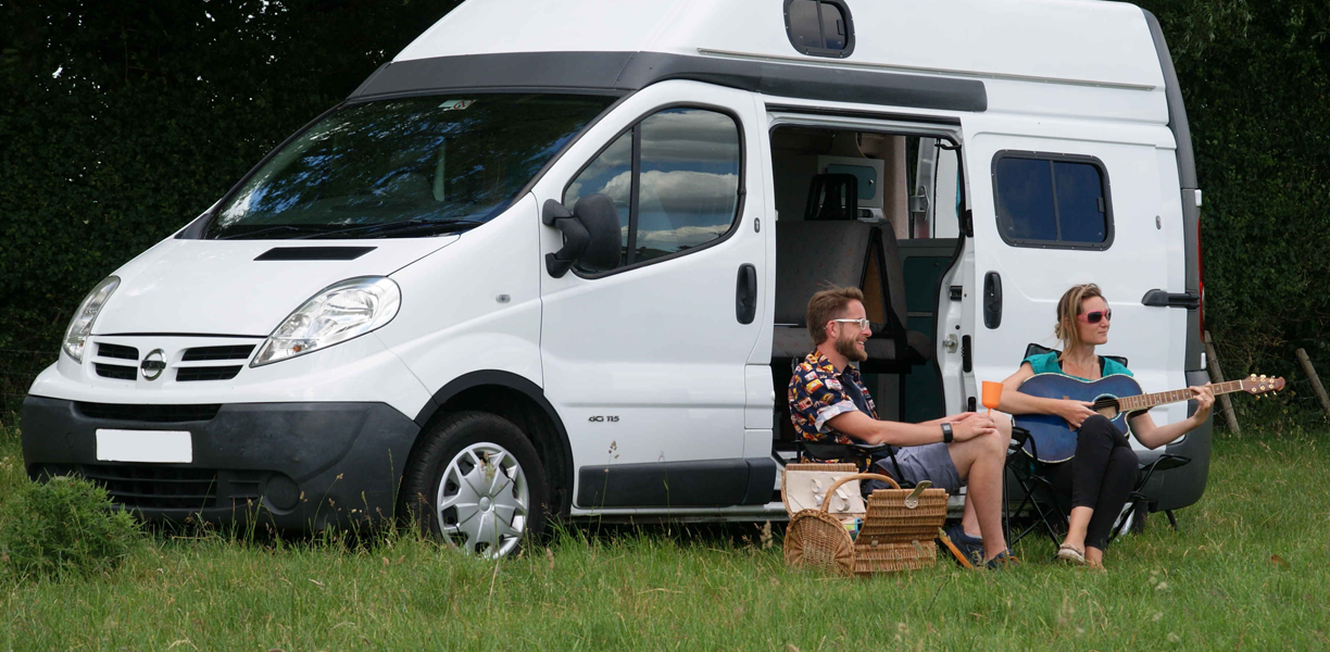 Couple sit outside campervan