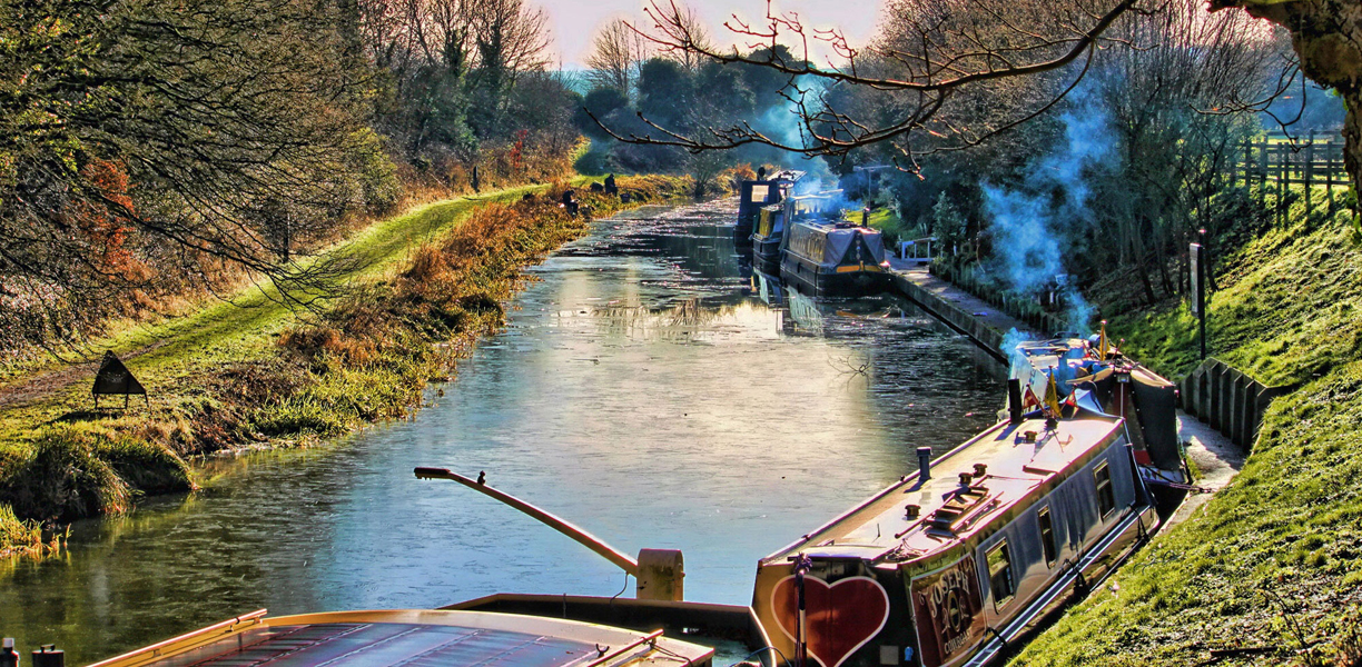 woodsmoke rising from chimneys of canal boats on the canal